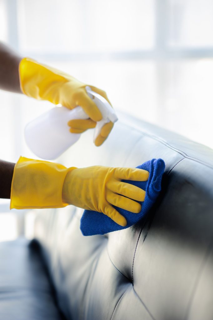 Person cleaning the room, cleaning staff is using cloth and spraying disinfectant.